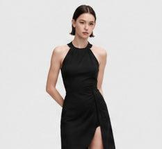 Black halter mini dress worn by a model against a light gray studio background